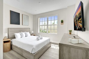 Une chambre d’hôtel moderne dotée d’un grand lit, d’un bureau, d’une télévision et d’une fenêtre offrant une vue agréable.