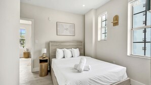 Un dormitorio con cama, mesita de noche, lámpara y una obra de arte.