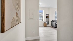 Un interior moderno con un pasillo que conduce a una sala de estar con un sofá gris y una mesa de centro.