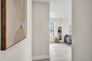 A modern interior with a hallway leading to a living area featuring a grey sofa and a coffee table. - Prime South Beach 1BR/1BA Beach 1 Min Away 301 (Miami Beach)