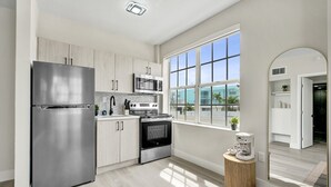 Eine moderne Küche mit Edelstahlgeräten, einem großen Fenster und Blick ins Freie.