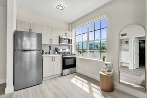 A modern kitchen with stainless steel appliances, a large window, and a view of the outside. - Modern 1BR South Beach Gem 1 Min Walk to Beach 201 (Miami Beach)