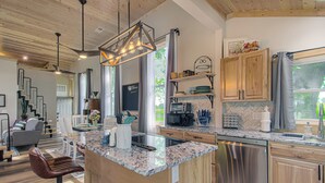 Une cuisine moderne dotée de plans de travail en granit, d’appareils électroménagers en acier inoxydable et d’armoires en bois.