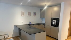 A modern kitchen with a central island, a built-in oven, and a sink. There are three framed pictures on the wall. - Alphubel Peak & Unlimited by Interhome (Saas-Fee)