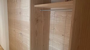 A wooden wardrobe with a pull-out shelf and a hanging rod. - Alphubel Peak & Unlimited by Interhome (Saas-Fee)