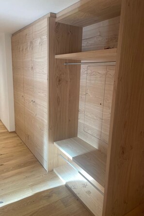 A wooden wardrobe with a pull-out shelf and a hanging rod. - Alphubel Peak & Unlimited by Interhome (Saas-Fee)