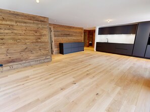 Eine moderne Küche mit Holzboden, eingebauten Schränken und einer zentralen Kochinsel.