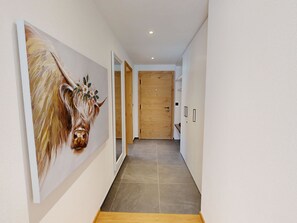 A hallway with a large painting of a horse, wooden flooring, and a wooden door at the end. - Alphubel Peak & Unlimited by Interhome (Saas-Fee)