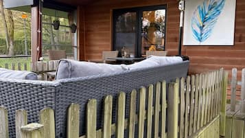 A cozy outdoor seating area with a wicker sofa and a wooden fence.