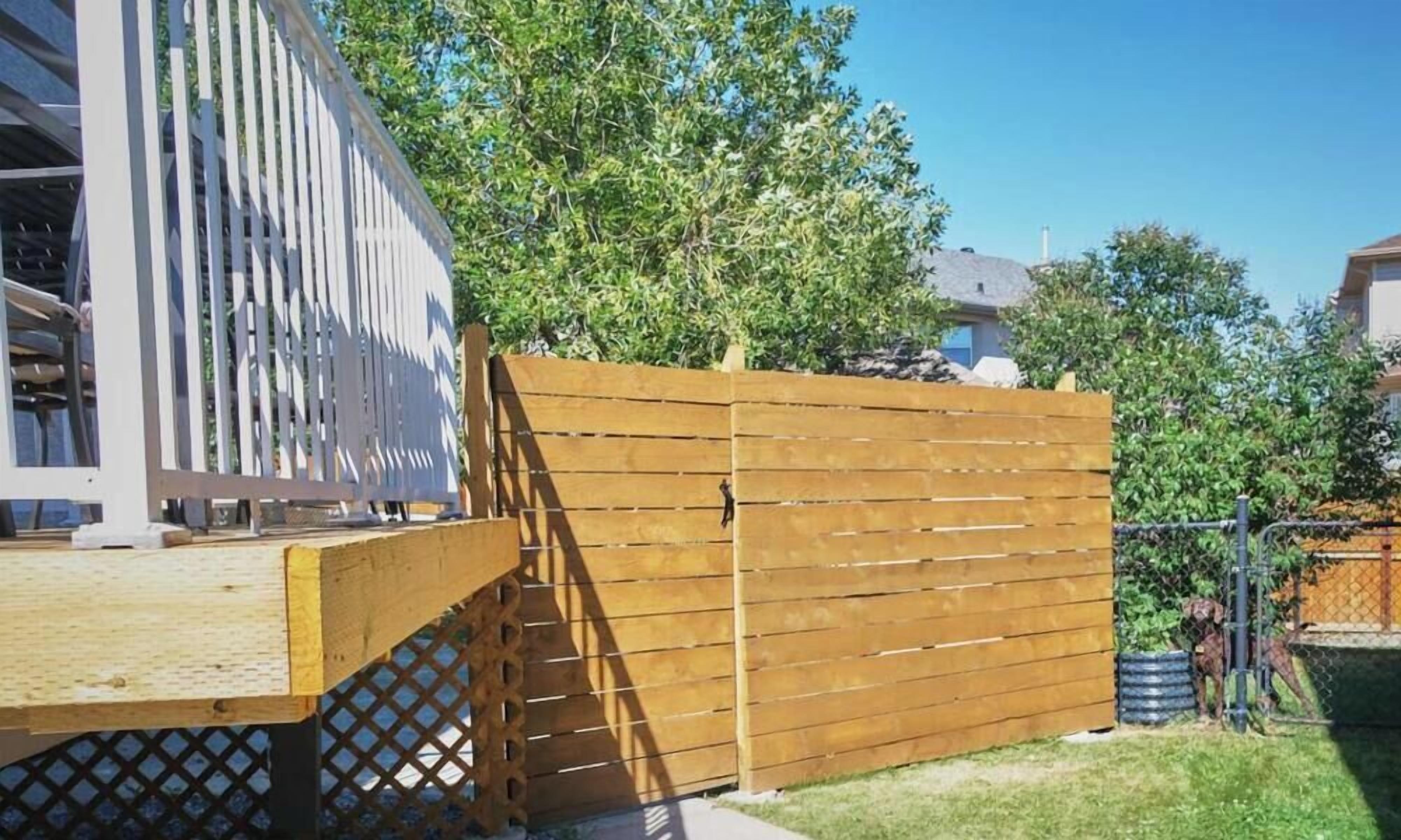 A wooden fence with a lattice section, a clear sky, and a grassy yard.