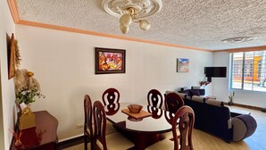 Un comedor con una mesa redonda y sillas, un ventilador de techo y un televisor en la sala.