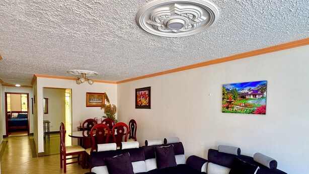 Una sala de estar con un sofá modular, un comedor con sillas y un cuadro en la pared.