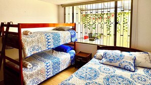 Una habitación con literas, una mesita pequeña y una ventana con barrotes.