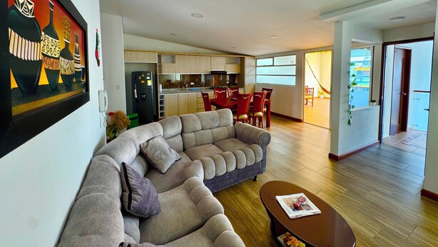 A modern living room with a sectional sofa, a dining area, and a kitchen. - Apartment with privileged location in Paipa (Paipa)