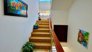 A staircase with a handrail, potted plants, and artwork on the walls. - Apartment with privileged location in Paipa (Paipa)