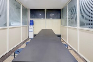 Una sala de conferències amb una taula llarga, cadires i un dispensador d'aigua.