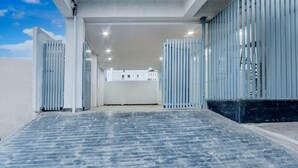 A modern building with a flat roof, large windows, and a paved entrance area. - Deluxenest Guest House (Hyderabad)
