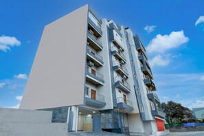 Ein mehrgeschossiges Wohnhaus mit Balkonen, einer Garageneinfahrt und blauem Himmel.