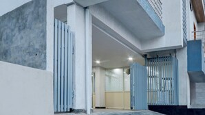 A modern building entrance with a concrete facade, a metal gate, and a tiled floor. - Deluxenest Guest House (Hyderabad)