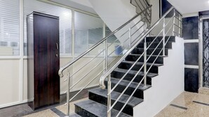 A staircase with metal railings, a dark wooden door, and a window with blinds. - Deluxenest Guest House (Hyderabad)
