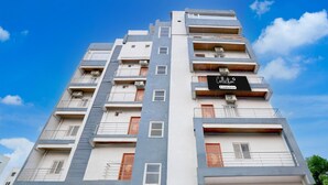 A multi-story building with balconies, a red garage door, and a sign that reads 'Collector.' - Deluxenest Guest House (Hyderabad)