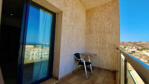 Un balcon avec vue sur la mer, une table et deux chaises.