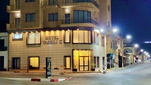 Un hôtel avec une enseigne indiquant « HÔTEL TASSILI II » et une entrée bien visible.