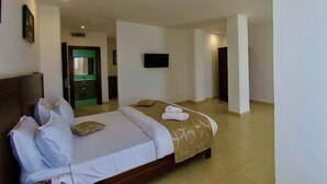 Une chambre d’hôtel avec un lit, une télévision et une salle de bain, le tout visible à travers une porte ouverte.