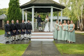 A gazebo with a white exterior and wooden steps leading up to it.