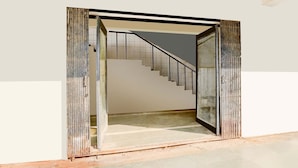 A staircase with a metal railing leading to a tiled floor. - Deluxeinfocity Metro Station Gandhinagar (Gandhinagar)