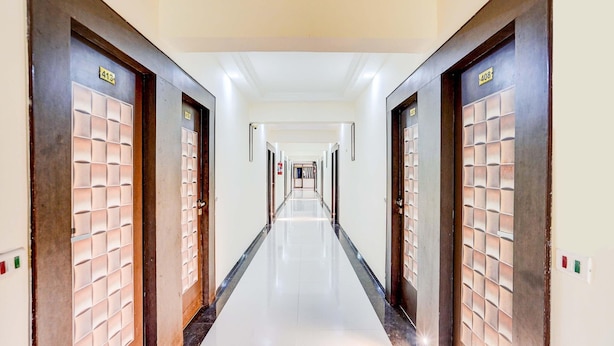 A long, narrow hotel corridor with doors on both sides, each marked with a number. - Deluxeinfocity Metro Station Gandhinagar (Gandhinagar)