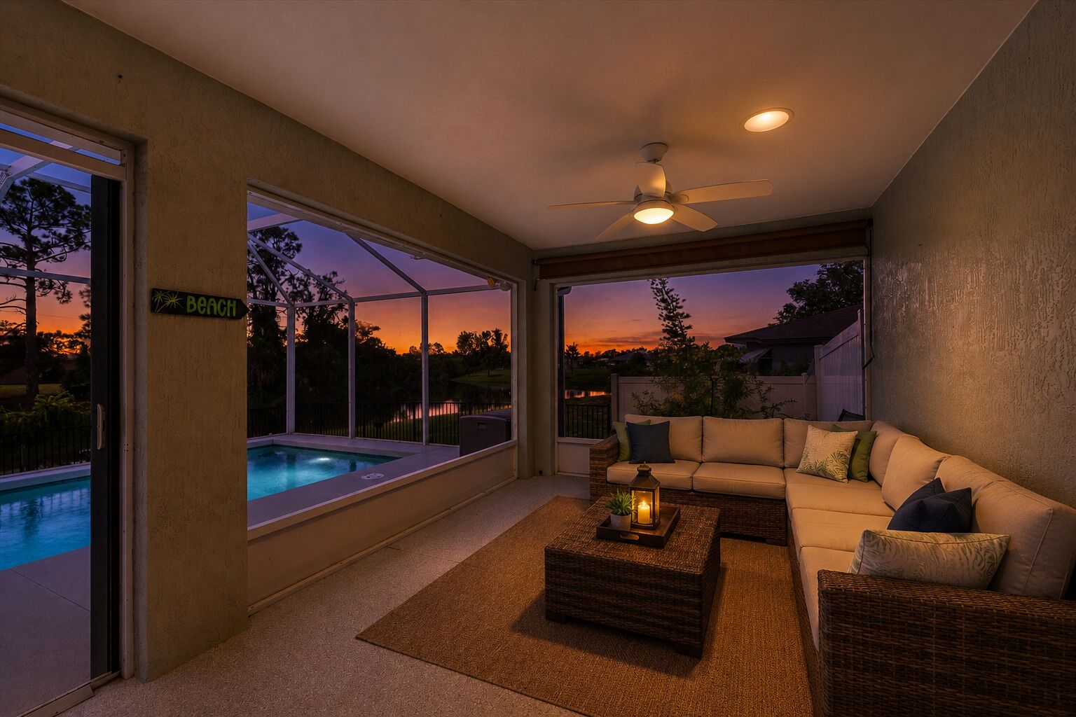 A modern living room with a pool, a ceiling fan, and a view of the sunset.