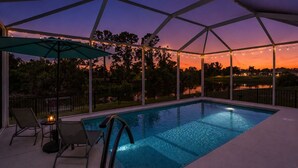 An outdoor swimming pool with a covered area, surrounded by trees and a view of a body of water. - Coastal Englewood Retreat near beaches, golf and relaxing sunsets (Englewood)