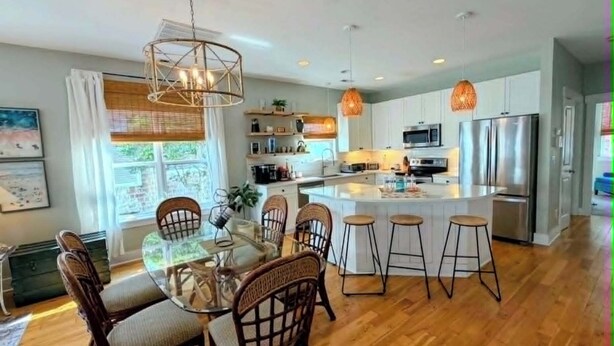 Una cucina moderna con isola centrale, pavimento in legno e illuminazione a sospensione.