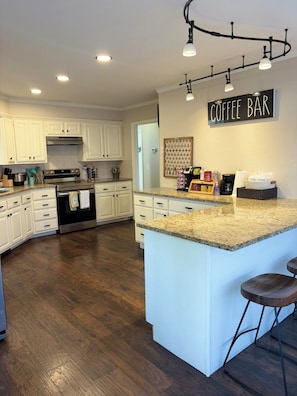 A kitchen with white cabinets, a granite countertop, a coffee bar, and a stainless steel oven. - 2-Story Central Edmond Home - 4 bed 2.5 bath (Edmond)
