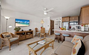 Ein Wohnzimmer mit Korbmöbeln, einem Flachbildfernseher und einem Deckenventilator.