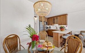 Eine moderne Küche mit Holzschränken, einer zentralen Kochinsel und einem Essbereich mit Korbstühlen und einem Glastisch.
