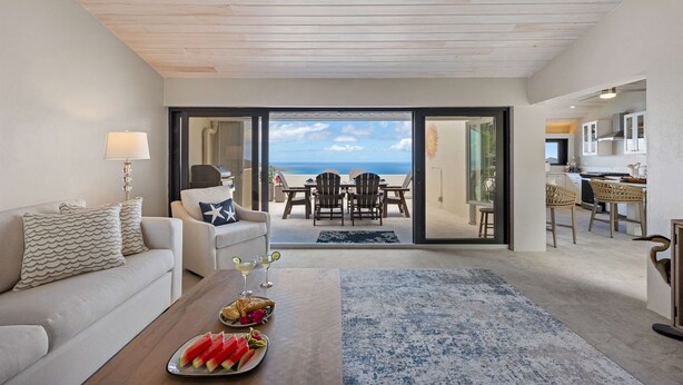 Ein Wohnzimmer mit einer Couch, einem Couchtisch mit Speisen und Blick ins Freie.