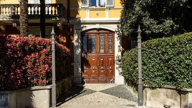 Un bâtiment doté d’une grande porte à double battant en bois, d’un chemin de pierre et d’une haie.