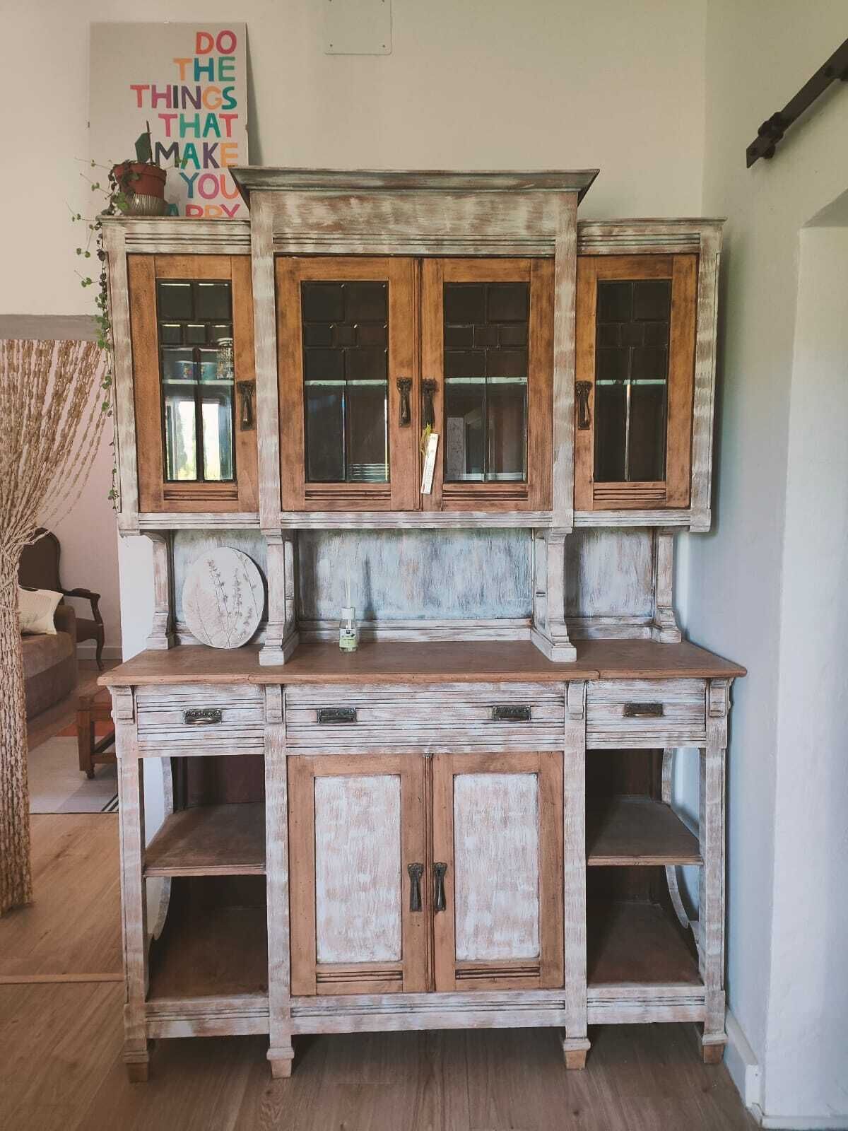 A rustic wooden cabinet with multiple doors and drawers, a decorative plate on top, and a motivational poster on the wall.