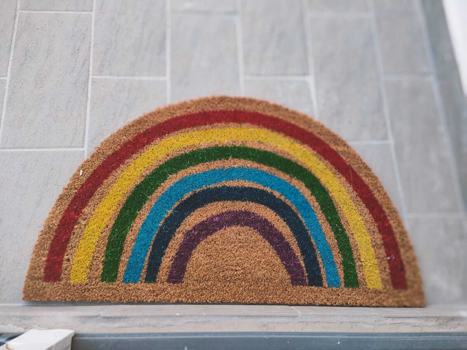 Eine Fußmatte mit Regenbogen-Design.