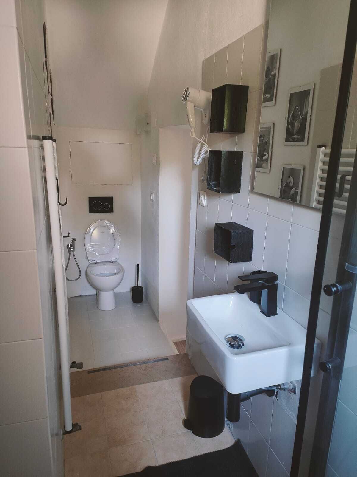Een badkamer met toilet, bidet, wastafel en een spiegel.
