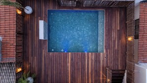 A rectangular pool with a wooden deck surrounding it, a clock, and a small plant.