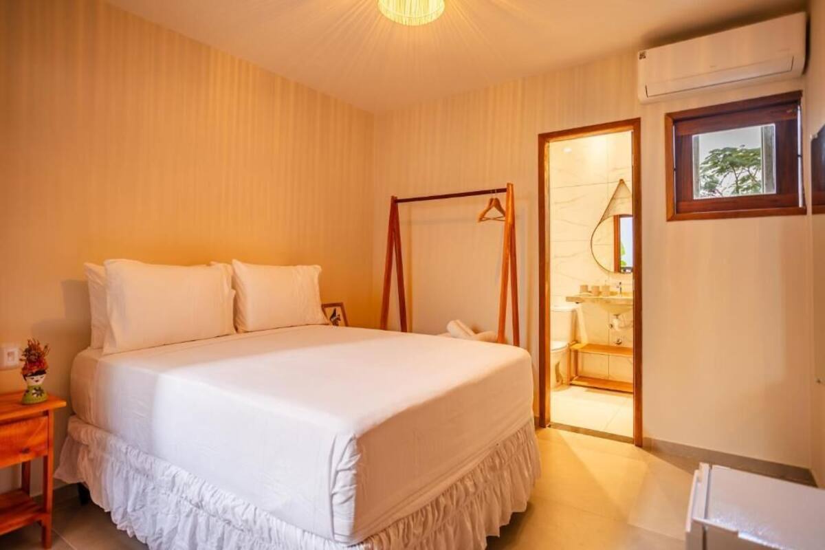 Quarto com cama, mesa de cabeceira e espelho.