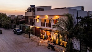 A two-story building with a balcony, a motorcycle parked in front, and a car parked on the street.