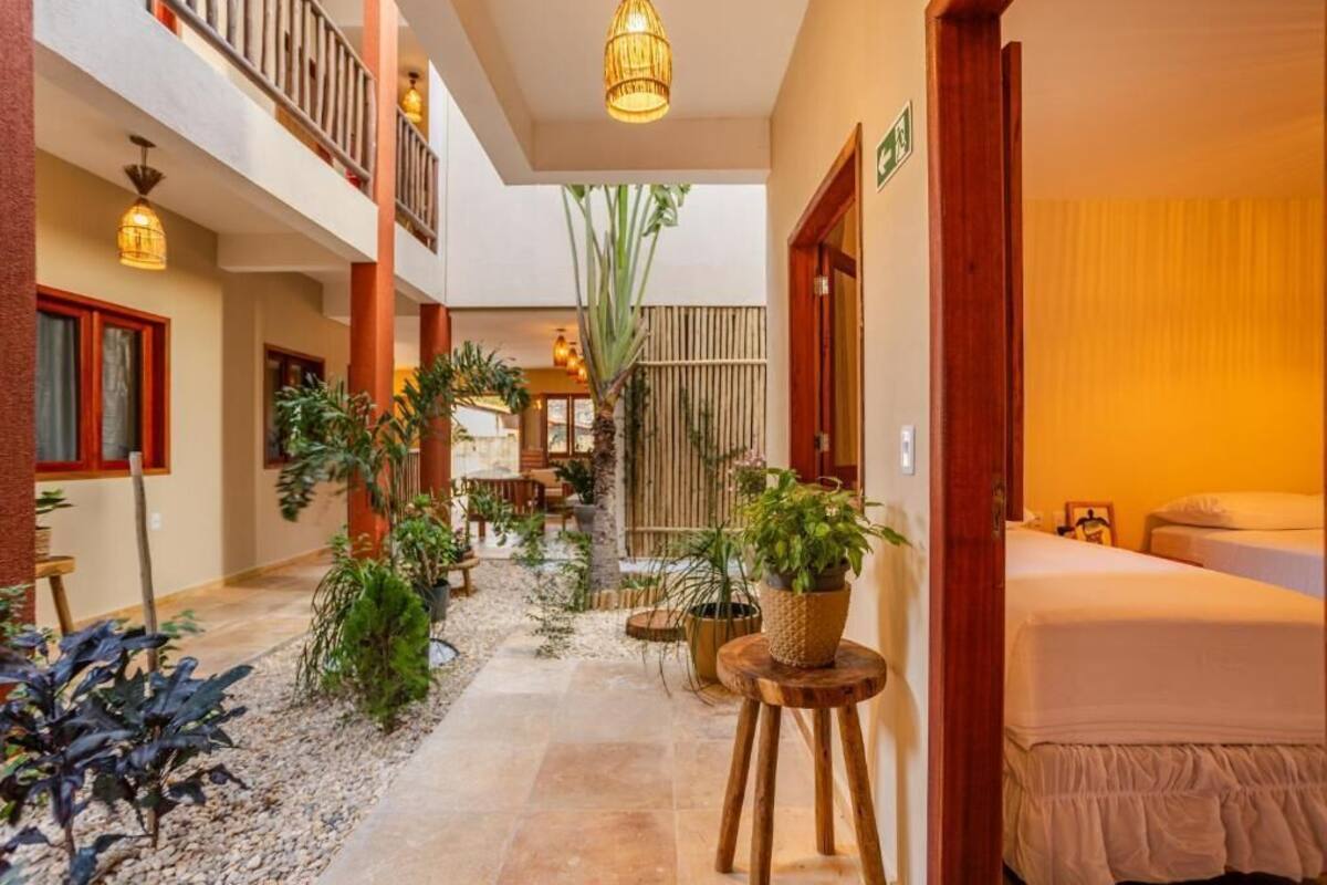 Corredor de hotel com uma cama, plantas em vasos e um espaço para refeições.