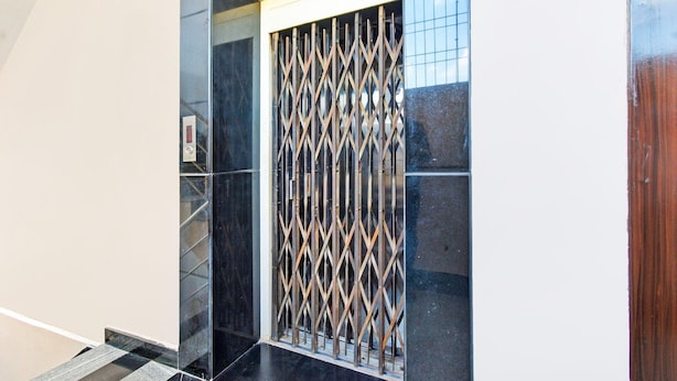 En moderne elevator med en dør af geometrisk metalgitter.