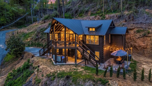 A log cabin with a balcony, outdoor seating, and a fire pit. - Indoor Private Pool, Sleeps 12, In Gatlinburg (Gatlinburg)