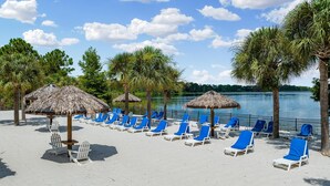 Una spiaggia con lettini e ombrelloni di paglia, una riva sabbiosa e un mare calmo.