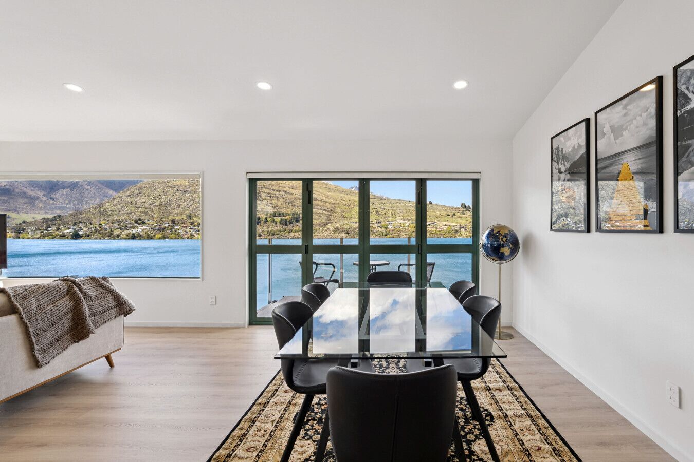 A modern room with a large window, a dining table, and a globe on the wall.